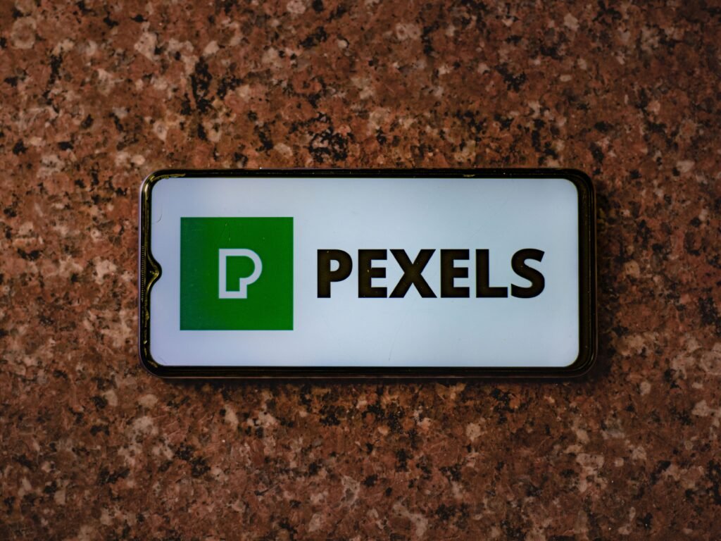 A smartphone displaying the Pexels app logo on a granite tabletop.
